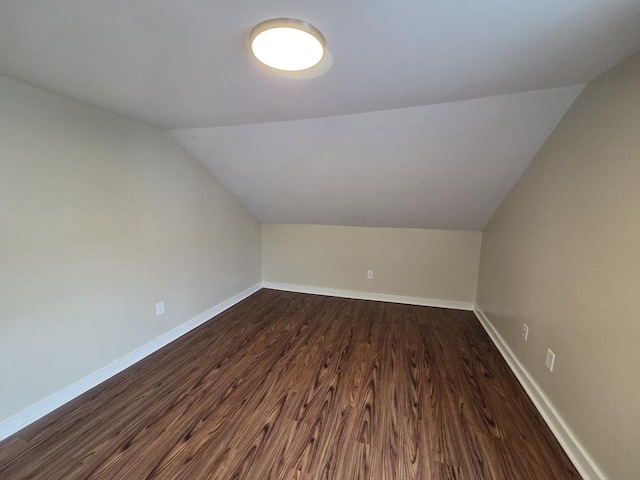 additional living space featuring dark wood-style flooring, baseboards, and lofted ceiling