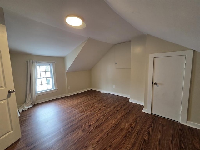 additional living space with baseboards, dark wood-style flooring, and lofted ceiling