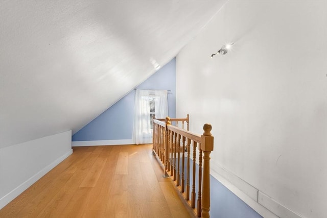 additional living space with vaulted ceiling and light wood-type flooring