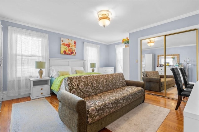 bedroom with crown molding, light wood-type flooring, and a closet