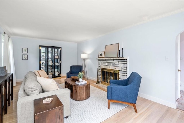 68 Shelton Rd, Swampscott, MA 01907 - living area with arched walkways, a stone fireplace, light wood-type flooring, ornamental molding, and baseboards