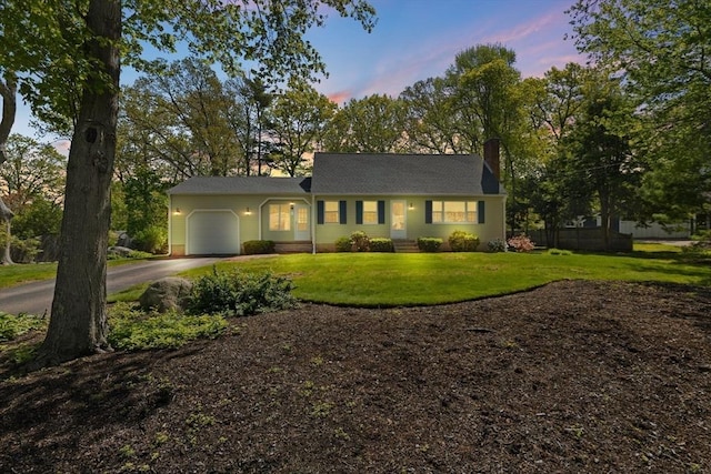 view of front of house featuring an attached garage, asphalt driveway, a front lawn, and a chimney