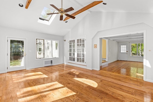 unfurnished living room featuring hardwood / wood-style flooring, beam ceiling, high vaulted ceiling, a ceiling fan, and a skylight