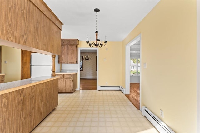kitchen featuring freestanding refrigerator, a chandelier, baseboard heating, and light countertops