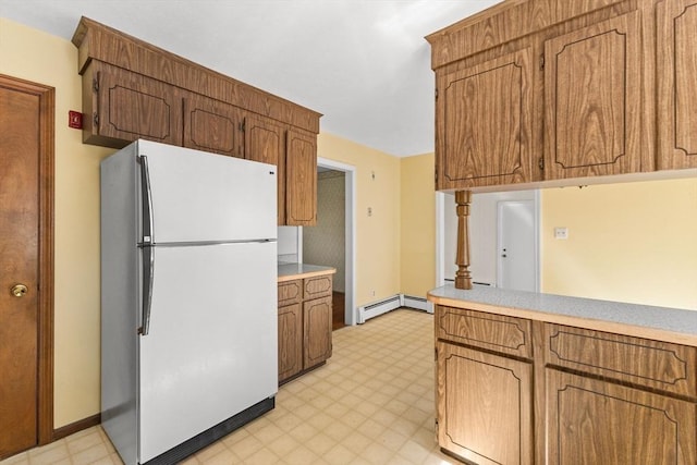 kitchen with freestanding refrigerator, light flooring, light countertops, and brown cabinetry