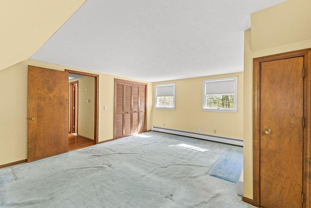 additional living space with a baseboard heating unit, carpet, and baseboards