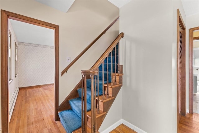 stairs featuring wood finished floors, a baseboard radiator, and baseboards