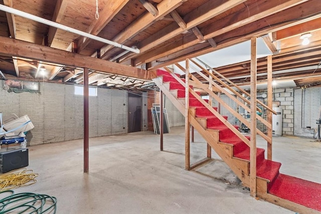 below grade area featuring stairs and electric water heater