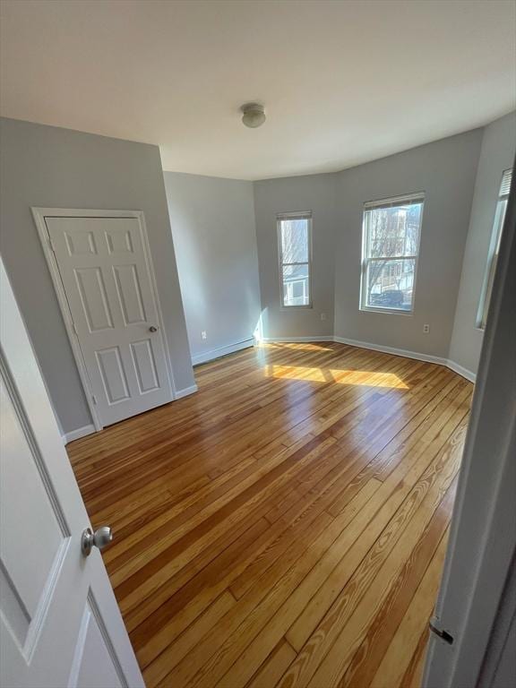 spare room with baseboards and light wood-type flooring