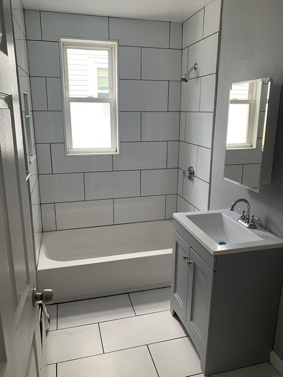 bathroom featuring plenty of natural light, shower / bathing tub combination, tile patterned flooring, and vanity