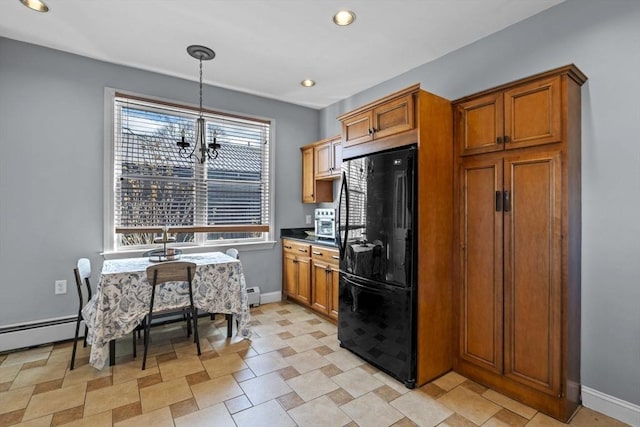 kitchen featuring brown cabinetry, freestanding refrigerator, and baseboards