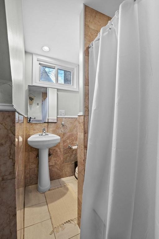 full bathroom with tile walls, tile patterned floors, and wainscoting