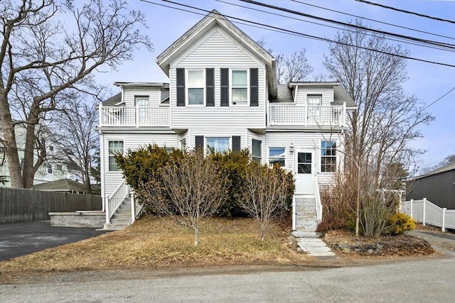 view of front of home featuring aphalt driveway, a balcony, and fence