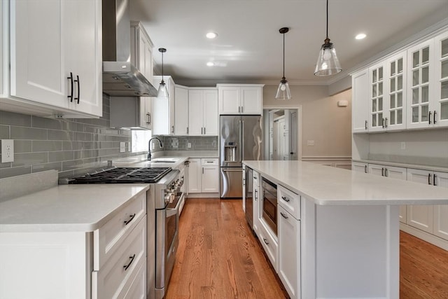kitchen featuring high quality appliances, a sink, light countertops, wall chimney exhaust hood, and a kitchen island
