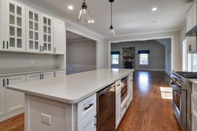 kitchen featuring crown molding, beverage cooler, appliances with stainless steel finishes, and a kitchen island