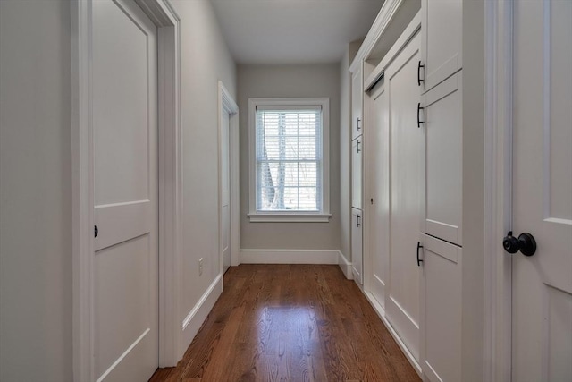 hall featuring dark wood-type flooring and baseboards