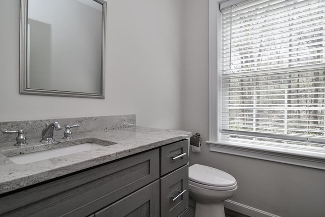 half bath featuring vanity, baseboards, and toilet