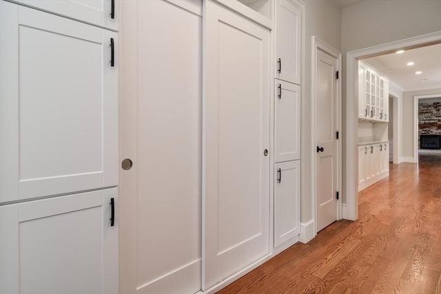 corridor with light wood-style floors, recessed lighting, and baseboards