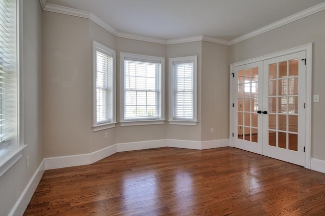 empty room featuring crown molding, baseboards, french doors, and wood finished floors