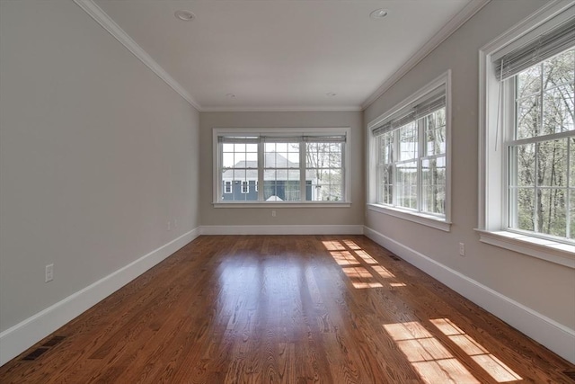 spare room featuring baseboards, ornamental molding, and wood finished floors