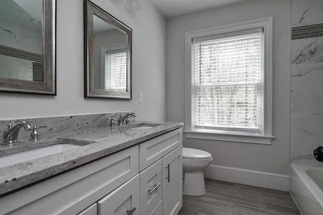 full bathroom featuring double vanity, a sink, baseboards, and toilet