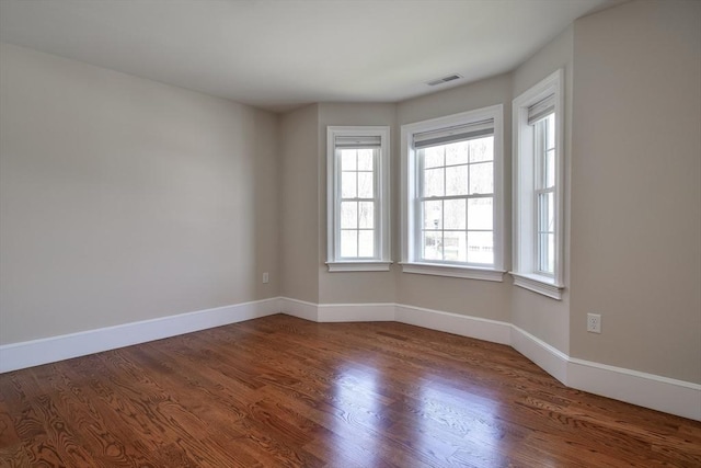 spare room with visible vents, baseboards, and wood finished floors