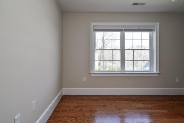 spare room featuring baseboards, visible vents, and wood finished floors
