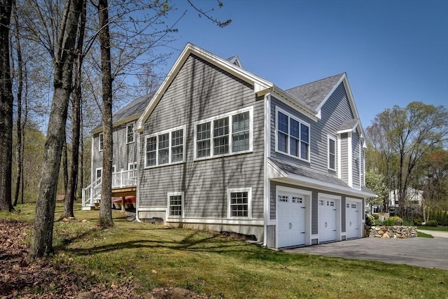 view of home's exterior featuring a lawn, an attached garage, a shingled roof, and aphalt driveway