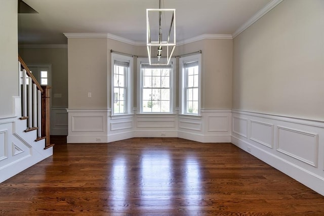 unfurnished dining area featuring crown molding, stairway, dark wood finished floors, and a wealth of natural light