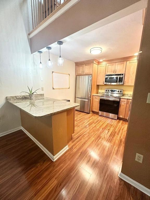 6 Tamarack Ln Unit 6, Peabody, MA 01960 - kitchen with stainless steel appliances, a peninsula, light wood-type flooring, and light brown cabinets