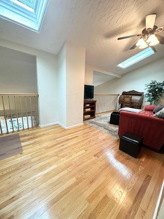 6 Tamarack Ln Unit 6, Peabody, MA 01960 - bedroom featuring a skylight, vaulted ceiling, wood finished floors, a ceiling fan, and a textured ceiling