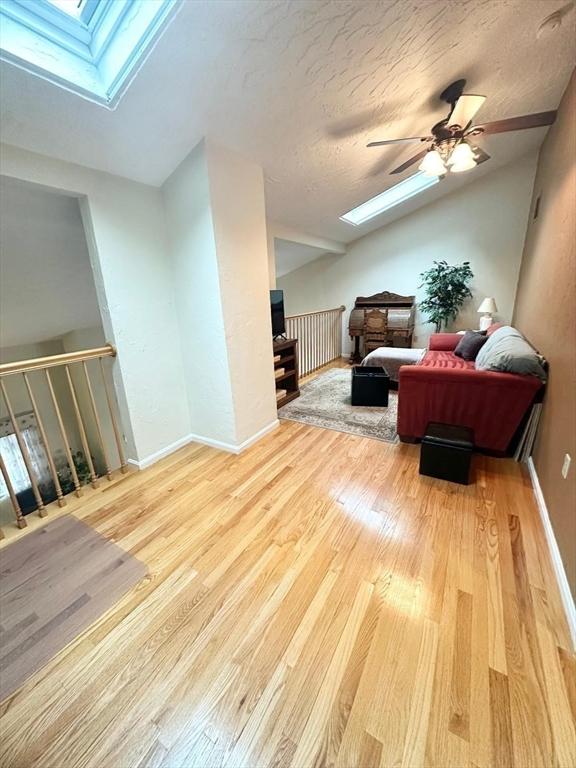 6 Tamarack Ln Unit 6, Peabody, MA 01960 - living room featuring a skylight, vaulted ceiling, wood finished floors, and ceiling fan