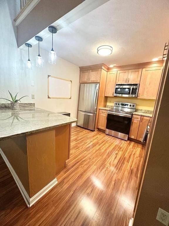 6 Tamarack Ln Unit 6, Peabody, MA 01960 - kitchen featuring appliances with stainless steel finishes, a peninsula, light wood-type flooring, and light stone countertops