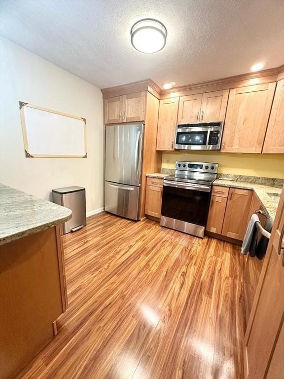 6 Tamarack Ln Unit 6, Peabody, MA 01960 - kitchen featuring stainless steel appliances, light wood-style flooring, a textured ceiling, light stone counters, and light brown cabinets