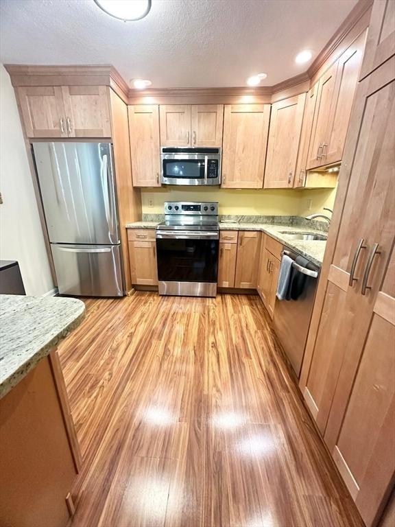 6 Tamarack Ln Unit 6, Peabody, MA 01960 - kitchen with appliances with stainless steel finishes, light wood finished floors, light brown cabinetry, light stone countertops, and a textured ceiling