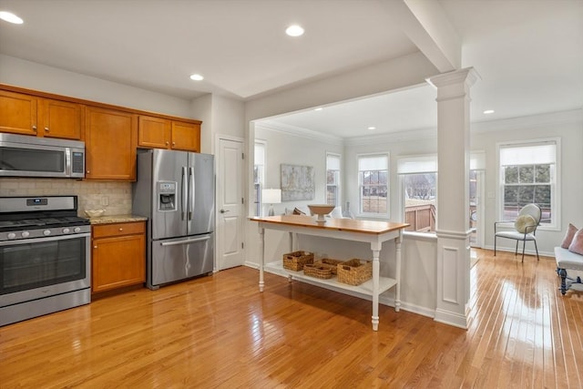 kitchen with backsplash, light wood-style floors, appliances with stainless steel finishes, brown cabinetry, and ornate columns