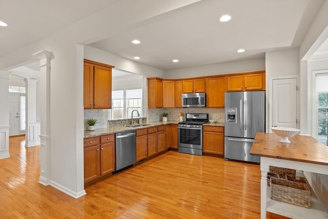 kitchen featuring a sink, decorative columns, brown cabinets, and appliances with stainless steel finishes