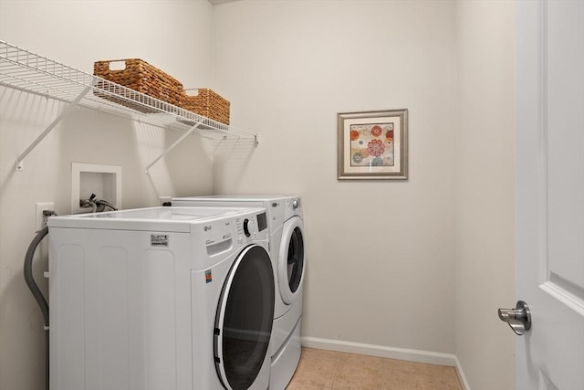 clothes washing area featuring laundry area, light tile patterned floors, baseboards, and washer and clothes dryer