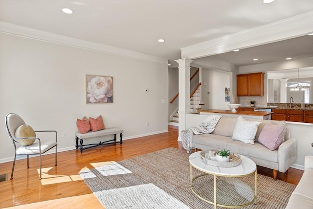 living room featuring stairway, light wood-style flooring, baseboards, and ornamental molding