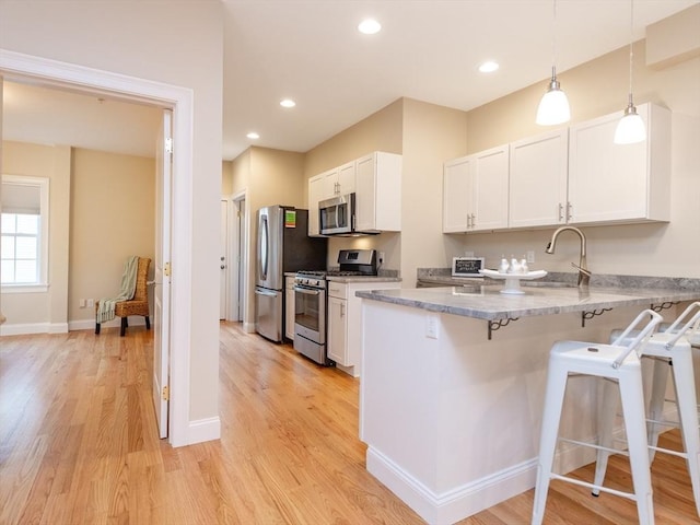 170 I St Unit 1, Boston, MA 02127 - kitchen featuring appliances with stainless steel finishes, a breakfast bar, a sink, white cabinetry, and light wood-type flooring