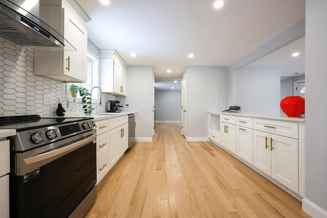 kitchen with light wood-style flooring, backsplash, appliances with stainless steel finishes, white cabinetry, and wall chimney exhaust hood