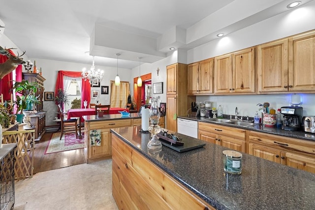 kitchen with sink, an inviting chandelier, dark stone countertops, white dishwasher, and pendant lighting