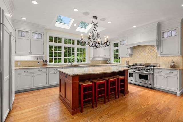 kitchen featuring sink, a breakfast bar area, decorative light fixtures, high quality appliances, and a kitchen island