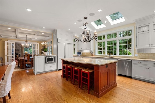 kitchen featuring a kitchen island, built in appliances, a notable chandelier, and decorative light fixtures