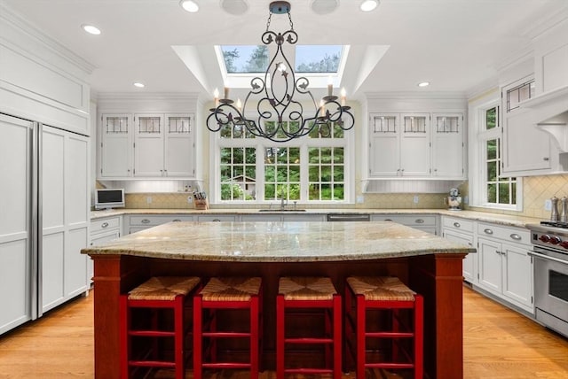 kitchen with a breakfast bar area, light stone counters, a center island, pendant lighting, and high end stove