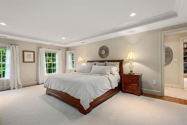 bedroom featuring multiple windows, a tray ceiling, light carpet, and crown molding