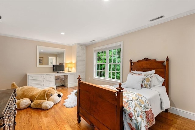 bedroom featuring built in desk, ornamental molding, and light wood-type flooring