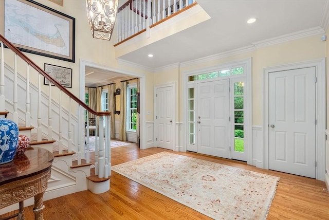 entrance foyer featuring ornamental molding, a chandelier, and light hardwood / wood-style floors