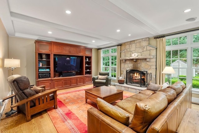 living room with beamed ceiling, a fireplace, and light hardwood / wood-style flooring