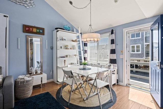 dining area with baseboards, an inviting chandelier, vaulted ceiling, and light wood-type flooring
